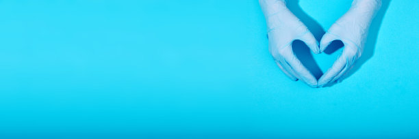 医生的手戴着医用手套，形状为心蓝色背景图片下载