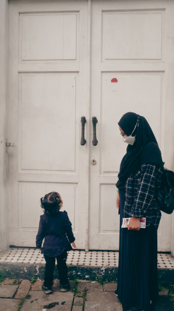 一位戴头巾的母亲和她的女儿站在一扇白色的门前图片下载