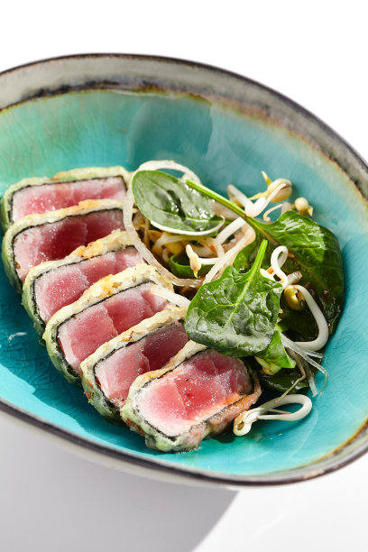 烤金枪鱼。切成薄片的生鱼片。金枪鱼tataki配上美味的柑橘柚子tataki酱。日本海鲜在黑色盘子孤立在白色背景上。图片下载