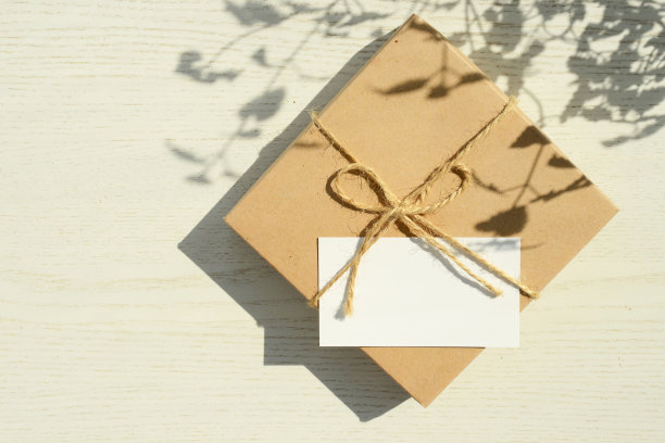 礼品盒和空白贺卡在白色的木制桌子上，草或植物的阴影，复制空间图片下载