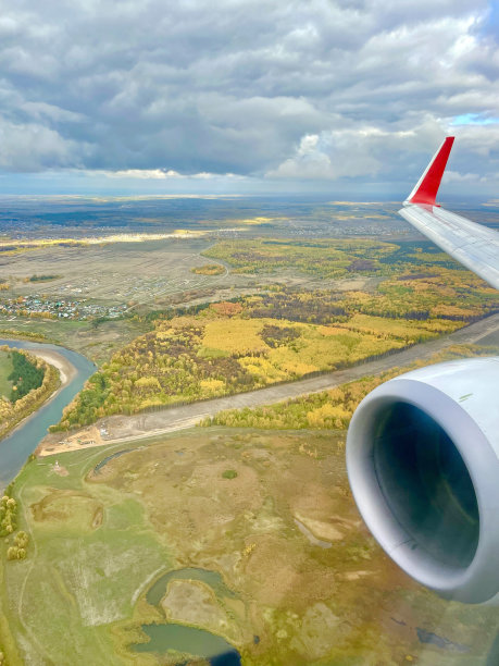 飞机机翼窗口查看飞行照片图像到秋天的森林，云天空和飞机引擎，自然上面的景观从喷气机翼，飞机旅行飞河和国家风景图片下载