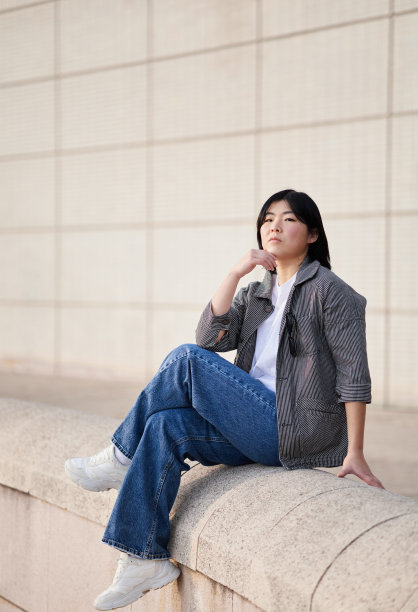 一个年轻的亚洲妇女穿着休闲服坐着的垂直照片。图片下载