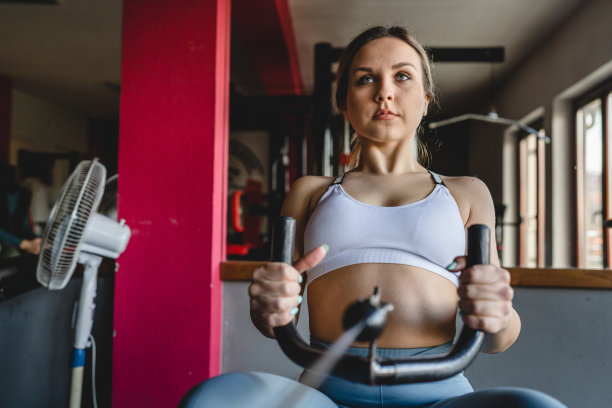 一名女子年轻的成年白人女性训练后，在健身房里的机器上穿着白色的黑色照片，真实的人复制空间的正面视图图片下载