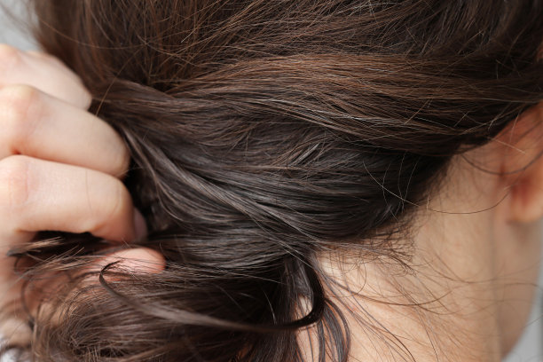 女孩用手抓着棕色的头发，开始白发特写。图片下载