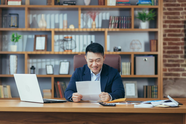 一个成功的商人画像，亚亚收到了银行的批准信，延长了信贷额度，一个快乐的人在桌子前工作，手里拿着一个信封图片下载