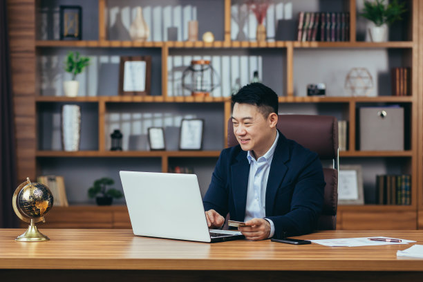 成功和快乐的商人，在网上商店购物，在现代办公室工作的亚洲人，使用笔记本电脑，持有信用卡图片下载