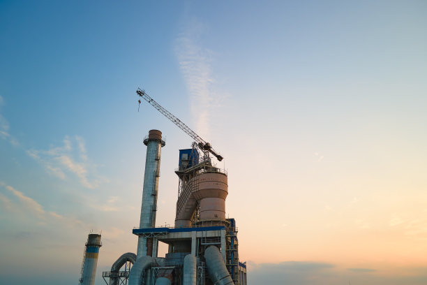 工业生产区具有高厂房结构和塔式起重机的水泥厂。制造业，全球工业和空气污染概念图片下载