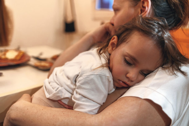 这个女孩睡在她妈妈的怀里。图片下载