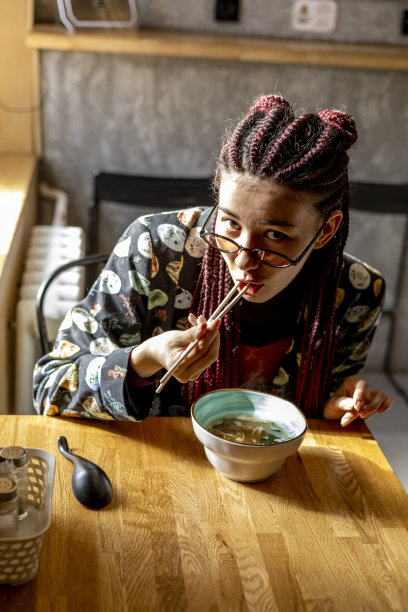 年轻的亚洲妇女吃味增汤在咖啡馆。城市里各种各样的女孩。图片下载