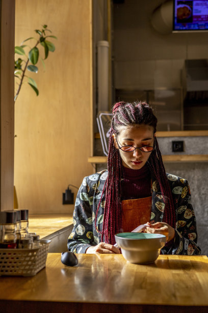 年轻的亚洲妇女吃味增汤在咖啡馆。城市里各种各样的女孩。图片下载