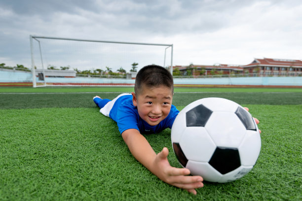 小男孩躺着，手里拿着一个足球图片下载