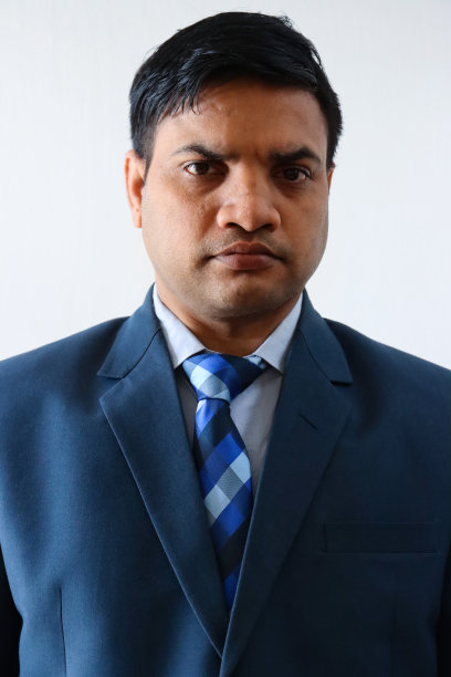 印度商人的特写形象，穿着漂亮的蓝色西装，白色的纽扣领衬衫和蓝色格子领带，摆姿势看着相机，头像图片下载