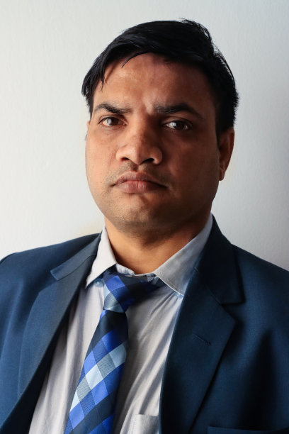 印度商人的特写形象，穿着漂亮的蓝色西装，白色的纽扣领衬衫和蓝色格子领带，摆姿势看着相机，头像图片下载