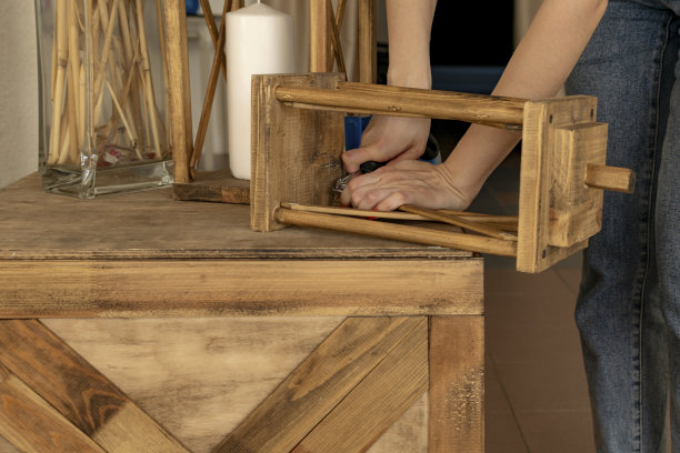 年轻女孩设计师修理旧的木制装饰路灯。我们正在为欢乐派对准备房间内部。图片下载