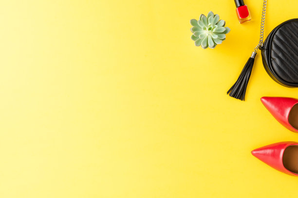概念女装与红色高跟鞋，钱包和指甲油的黄色背景与copyspace。俯视图图片下载