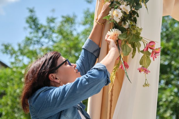 在婚礼拱门上做花卉装饰的女人图片下载