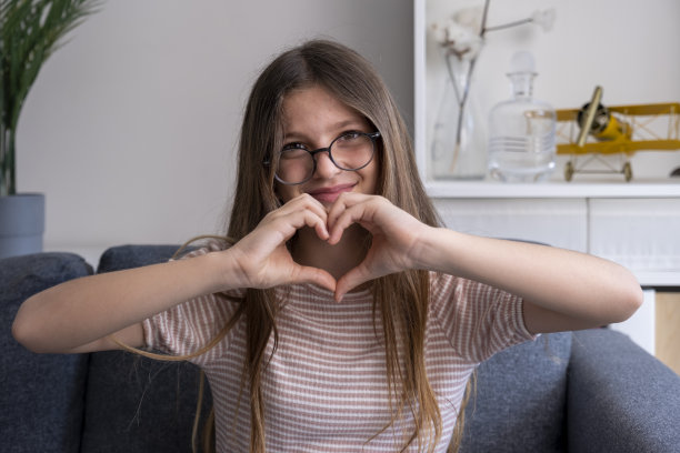 美丽的十几岁的女孩显示心脏的姿态图片下载