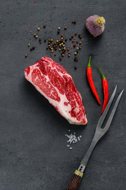新鲜生牛排配调味料，辣椒和肉叉，俯视图图片下载