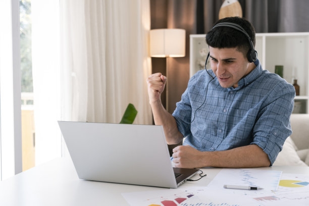 英俊的年轻人看着笔记本电脑屏幕非常高兴图片下载