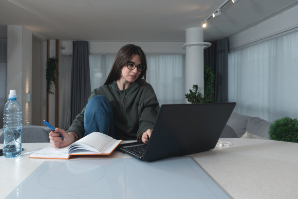 年轻的生病的女大学生坐在家里，通过笔记本电脑上的视频电话会议准备在线课程。在线互联网商务教育，保健理念。图片下载