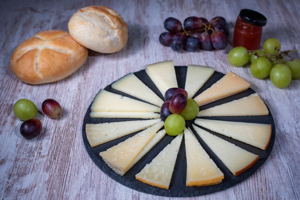 切成楔形的西班牙奶酪板，放在质朴的石头盘子上，配以葡萄、橄榄和面包。图片下载