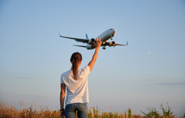女人挥手向着陆的商用飞机的背影图片下载