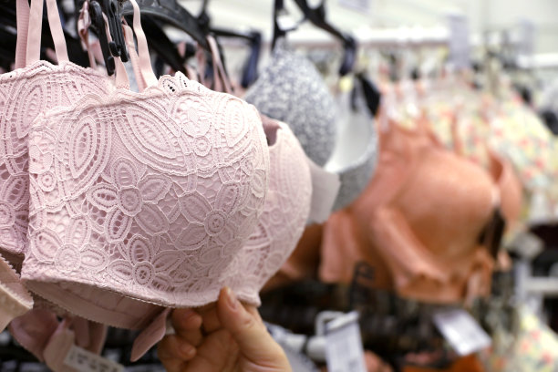 女人选择粉红色蕾丝胸罩挂在内衣店的架子上图片下载