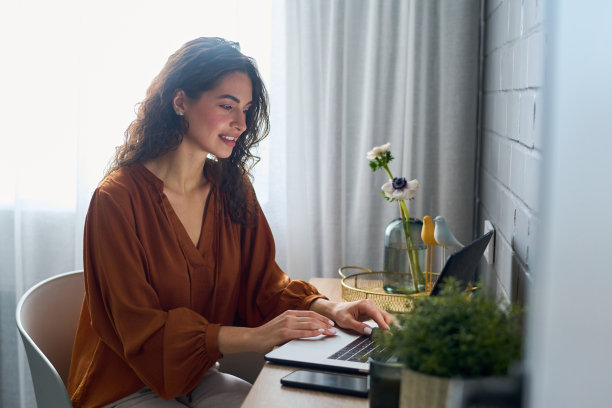 在家庭办公室网络期间，穿着衬衫的漂亮女孩看着笔记本电脑屏幕图片下载