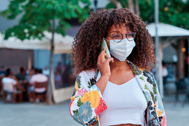 在冠状病毒爆发期间使用手机和戴口罩的年轻非洲裔美国女性图片下载