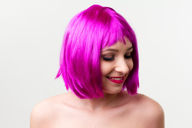 一个年轻女子的脸与明亮的化妆品在粉红色的背景聚集的头发在一个光滑的马尾。图片下载