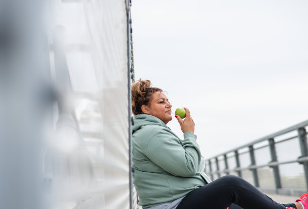 肥胖的拉丁妇女在减肥有氧训练后吃青苹果筋疲力尽图片下载
