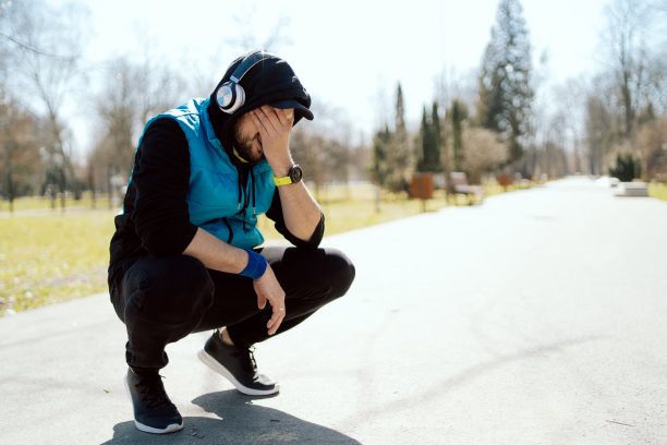 心碎的男子蹲在公园的人行道中央，运动员因体能不足而伤心，跑了几米后疲惫不堪，初学运动员，起步困难图片下载