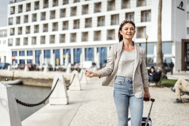 一个年轻快乐的女人带着行李在城市里散步的肖像图片下载