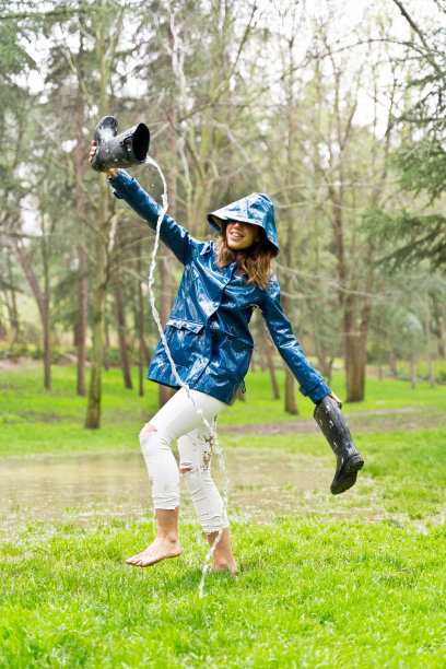 侧视图的妇女赤脚走在池塘空胶鞋与流的水。图片下载