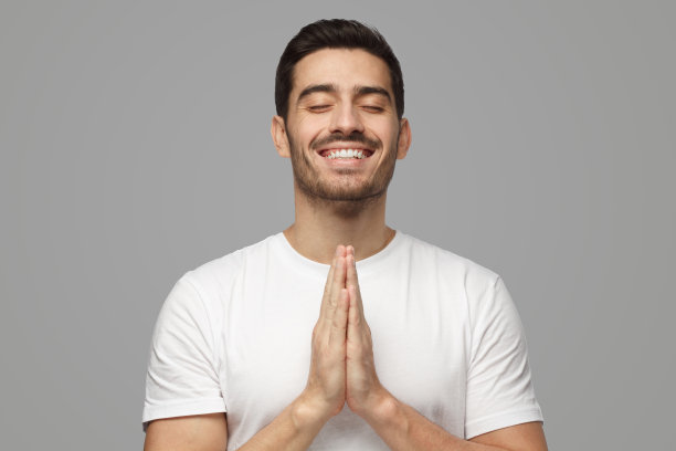 年轻人双手合十地祈祷或冥想，微笑着，梦想着，等待着图片下载