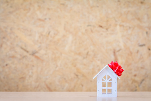 把买来的新楼盘作为礼物送给家人或所爱的概念，白色家居模型系上红丝带放在办公室的书桌上。图片下载