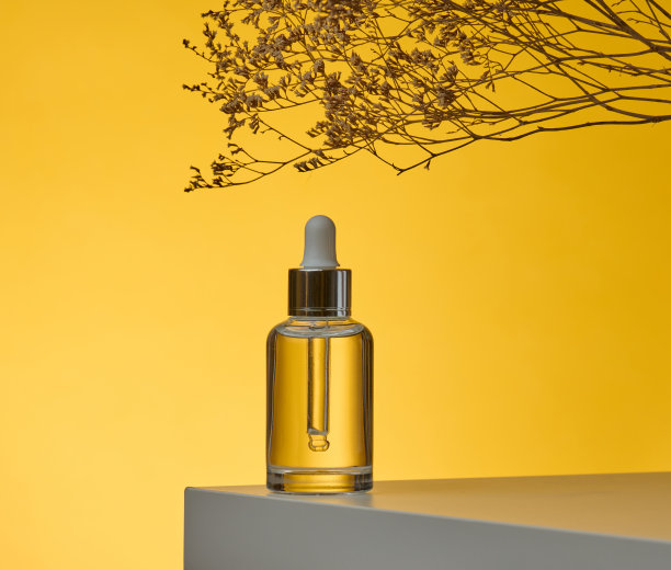 白色透明玻璃瓶与移液管化妆品，油，酸在一个白色的桌子上。黄色背景图片下载