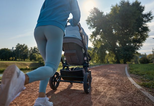 活跃的母亲慢跑。早上推着婴儿车慢跑或快步走的女人。母亲带着孩子在婴儿车里奔跑。图片下载