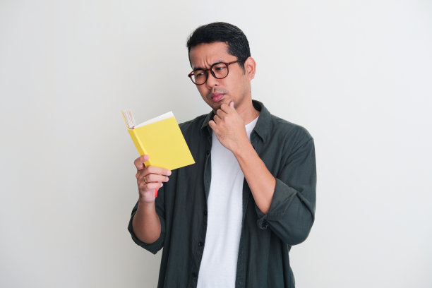 亚洲成年男子在看书时表情严肃图片下载
