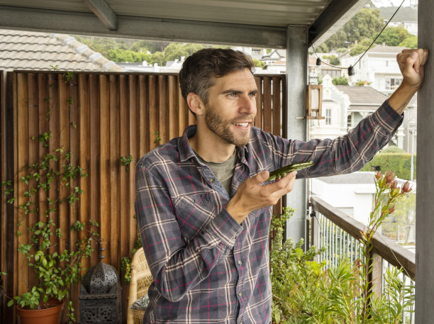 一个微笑着的年轻人正在自家院子里打电话图片下载
