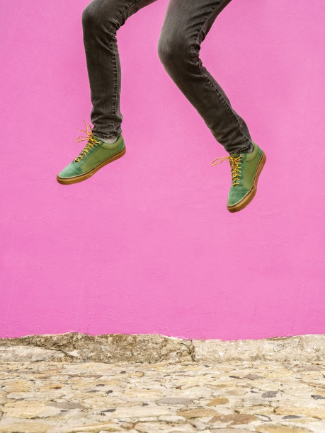 穿运动鞋的男人跳到粉红色的墙上图片下载