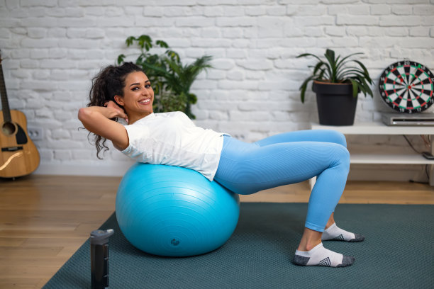 年轻漂亮的女运动员笑得很开心。在健身房的瑜伽课上用健身球做运动图片下载