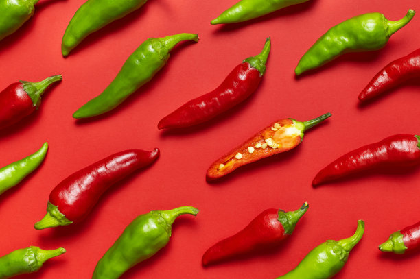 红辣椒和绿新鲜辣椒在红色背景平铺俯视图。菜肴调味料，烹饪用的香料，辣椒，食物。创意布局，辣椒图案图片下载