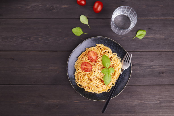 意大利意大利面，配上番茄、酱汁、帕尔马干酪和罗勒，底色为深色木质。图片下载