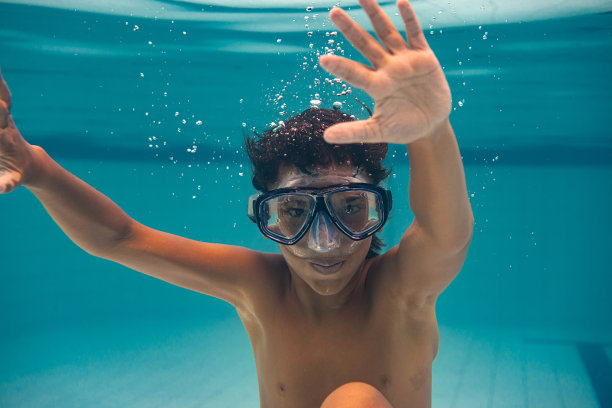 一个戴着潜水镜的男孩跳进了游泳池图片下载
