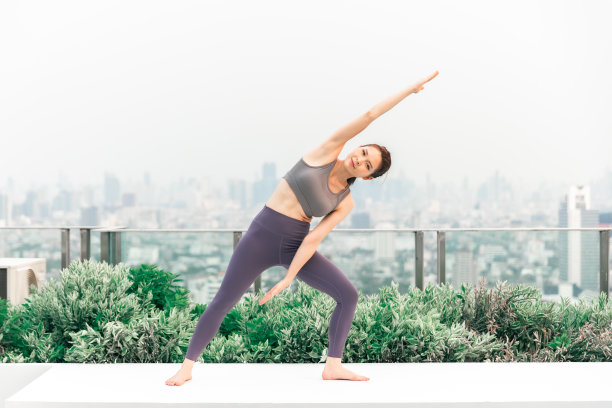 年轻的亚洲女子在屋顶上练习瑜伽。一群快乐的健身朋友在城市户外锻炼。图片下载