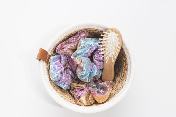 时髦全息闪亮金属发圈在篮子和竹制发刷白色背景图片下载