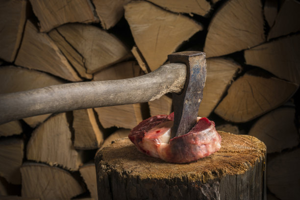 木斧插在厚牛排上，还有篝火。在满是烧烤木柴的柴棚前。图片下载