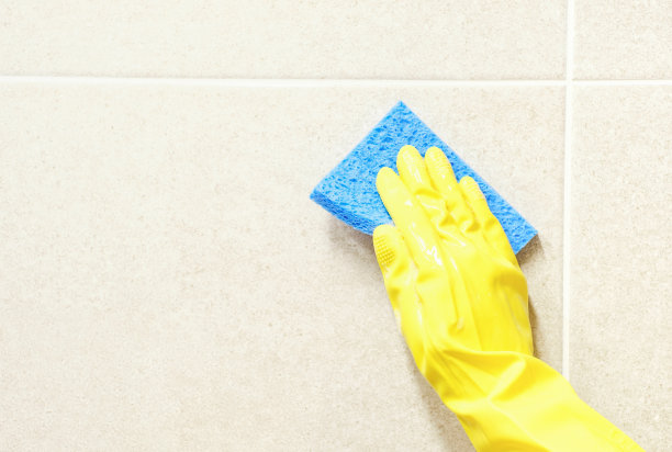 女人戴着黄色手套在浴室洗瓷砖的特写镜头。图片下载