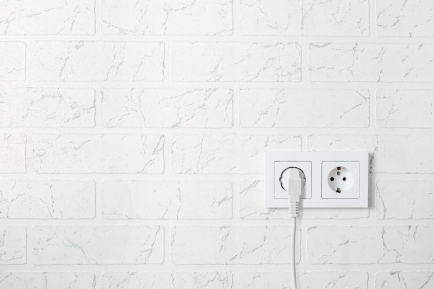 白色砖墙上的双白色方形玫瑰形，插座上有白色插头和白色电线图片下载